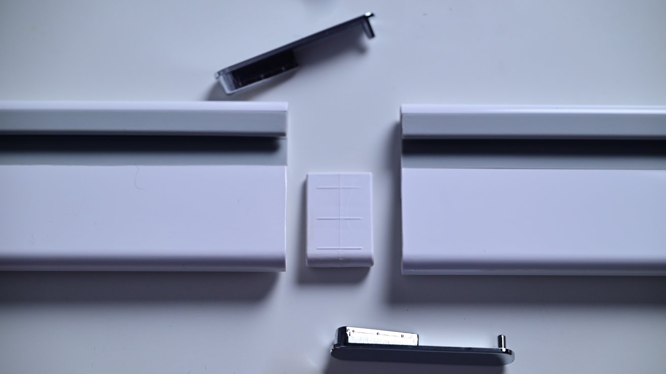 White plastic connector pieces and metal end caps arranged on a white surface for assembly or repair.